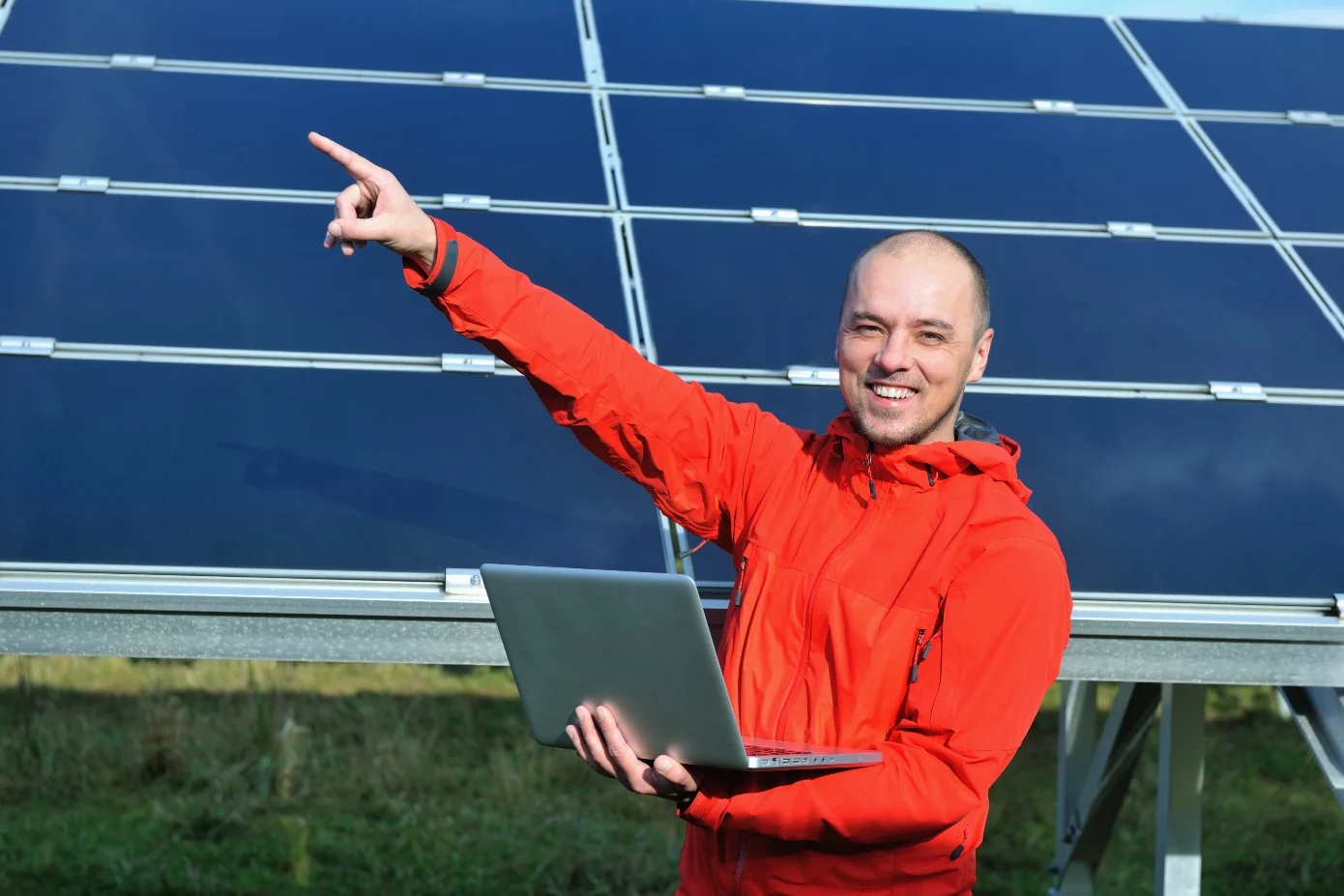 Homme devant un panneau solaire levant le doigt au ciel pour désigner les différents avantages de l'installation d'un champ de panneaux photovoltaïques