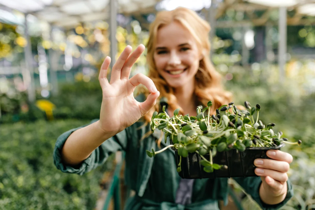 une fille souriante et qui montre ses plantations dans la main