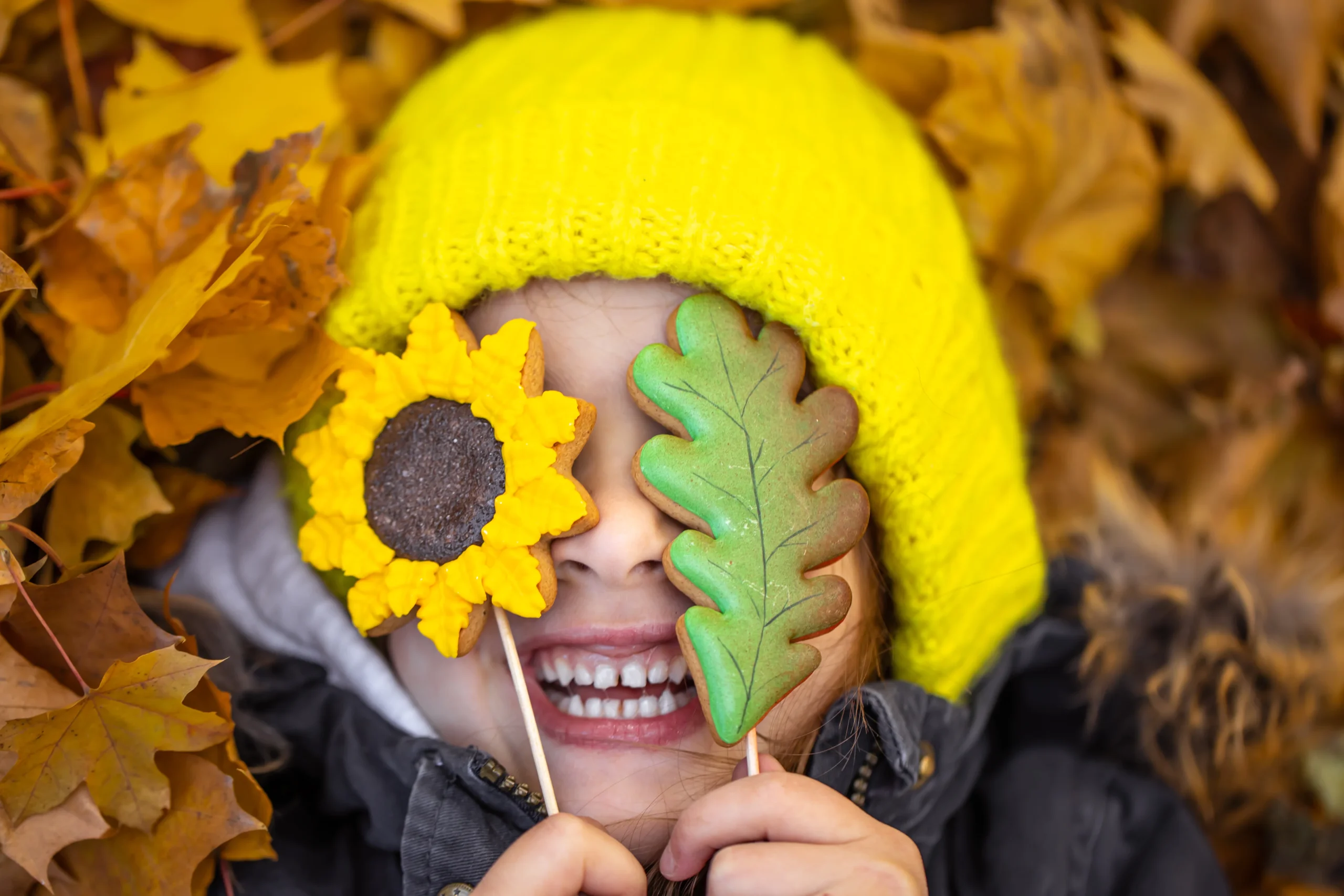 une petite fille rigole dans un parterre de feuilles
